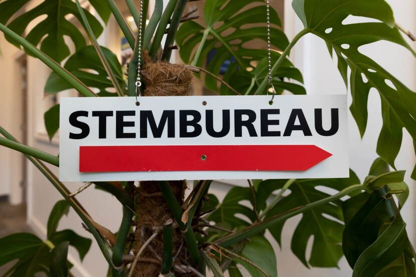 Bord stembureau met rode pijl naar rechts. Plant op achtergrond.